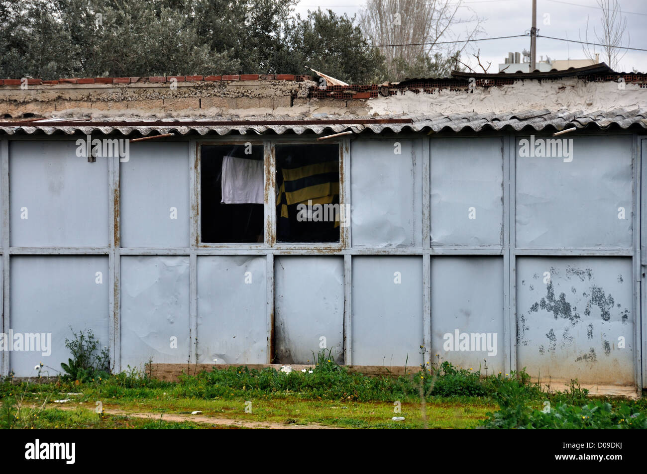 Rusty warehouse shack with drying laundry by the window. Stock Photo