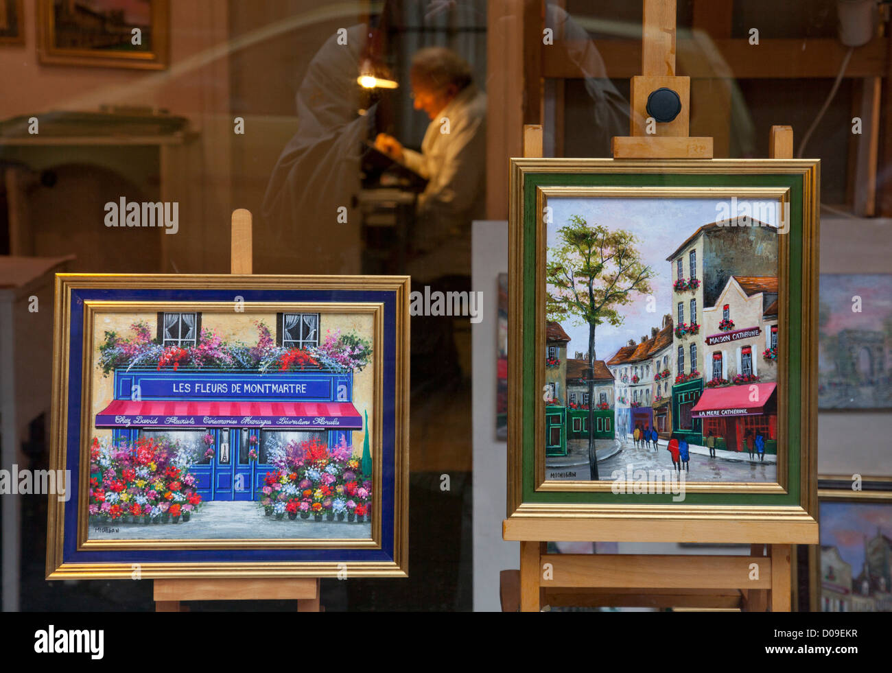Local artist painting in his studio , with paintings for sale in