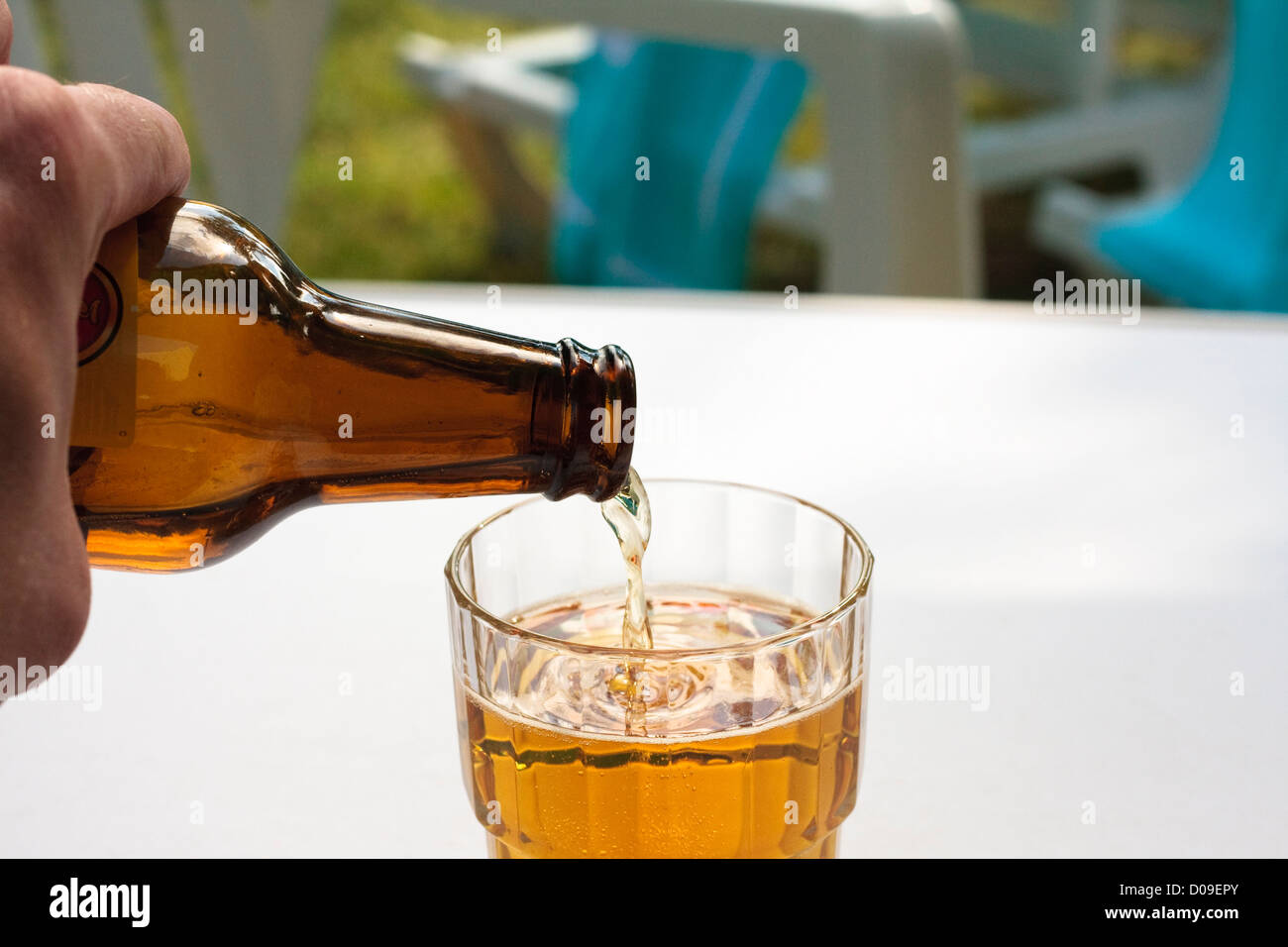 Beer being poured from a bottle into a glass by hand Stock Photo