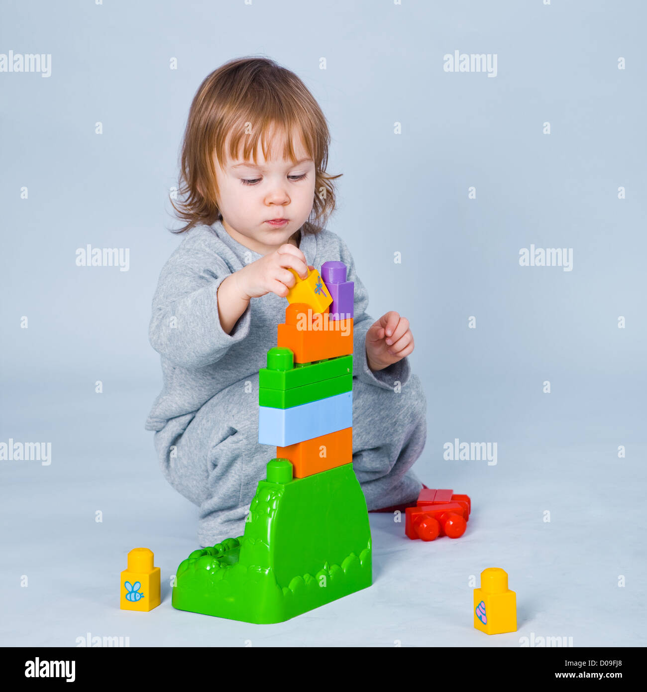 Child playing with constructor building pyramid on gray studio ...