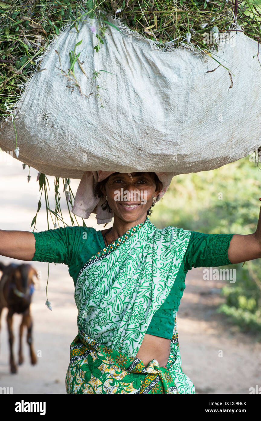 Rural Indian village woman carrying a sack of cut grass on her head. Andhra Pradesh, India Stock Photo