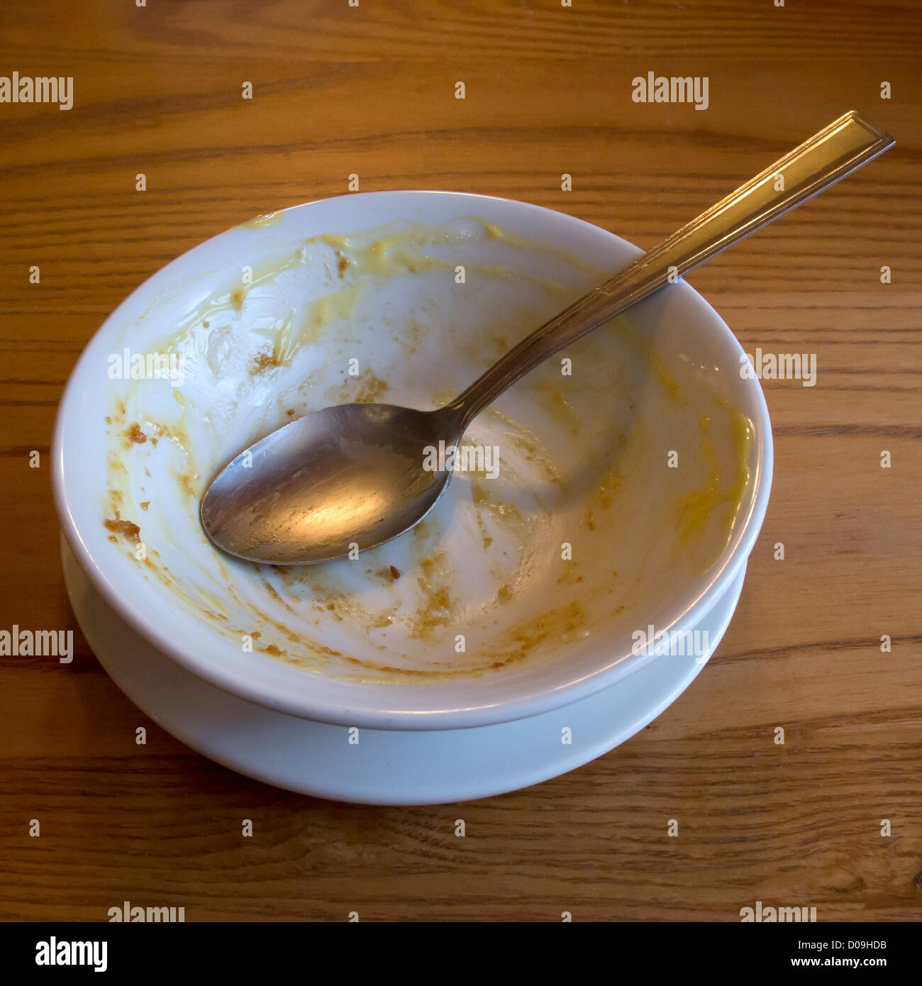 Empty used pudding bowl and spoon empty bowl of custard traditional british pudding treacle syrup pudding sponge and custard Stock Photo