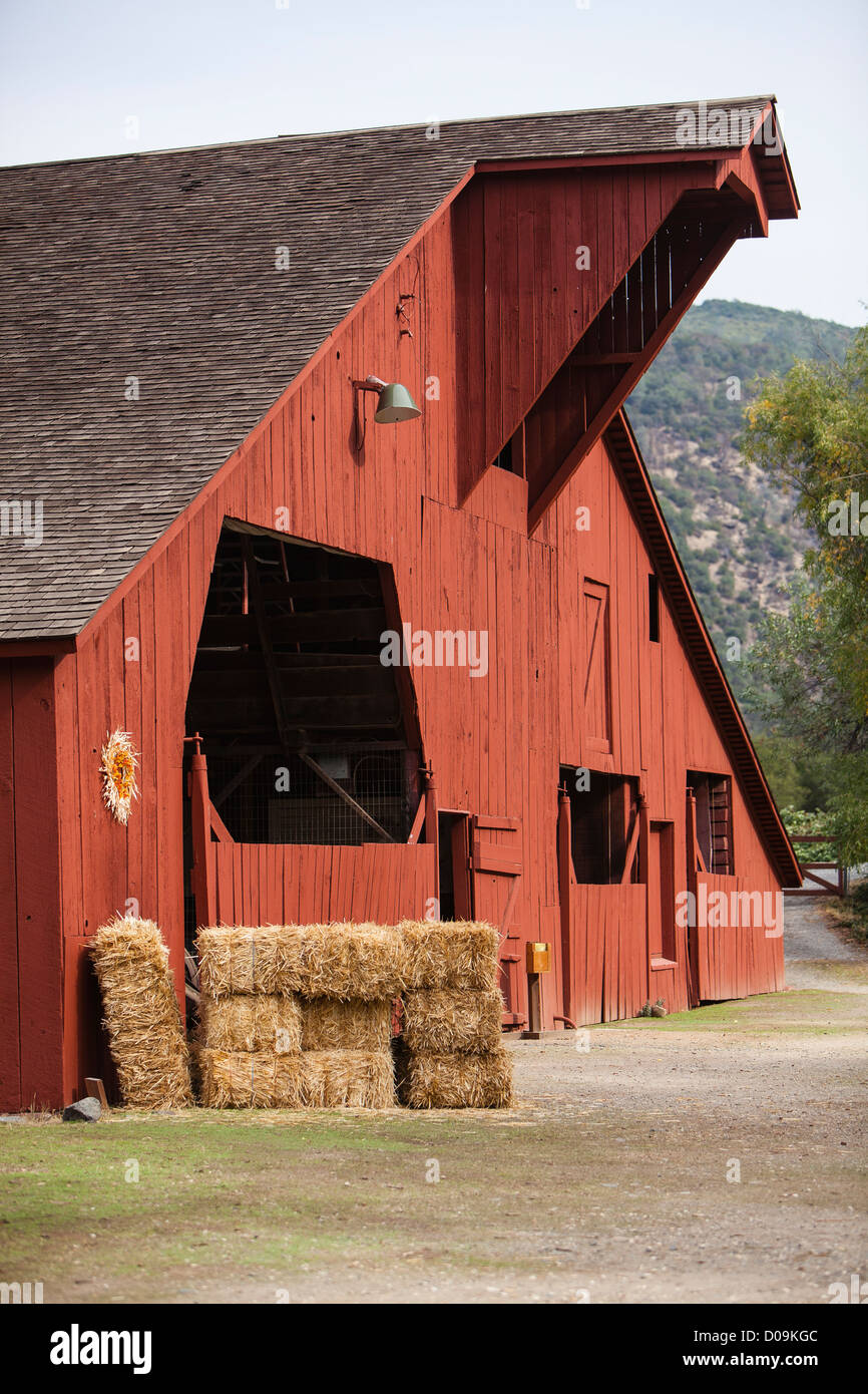 Typical red wood barn with hay bales stacked in front of it in the