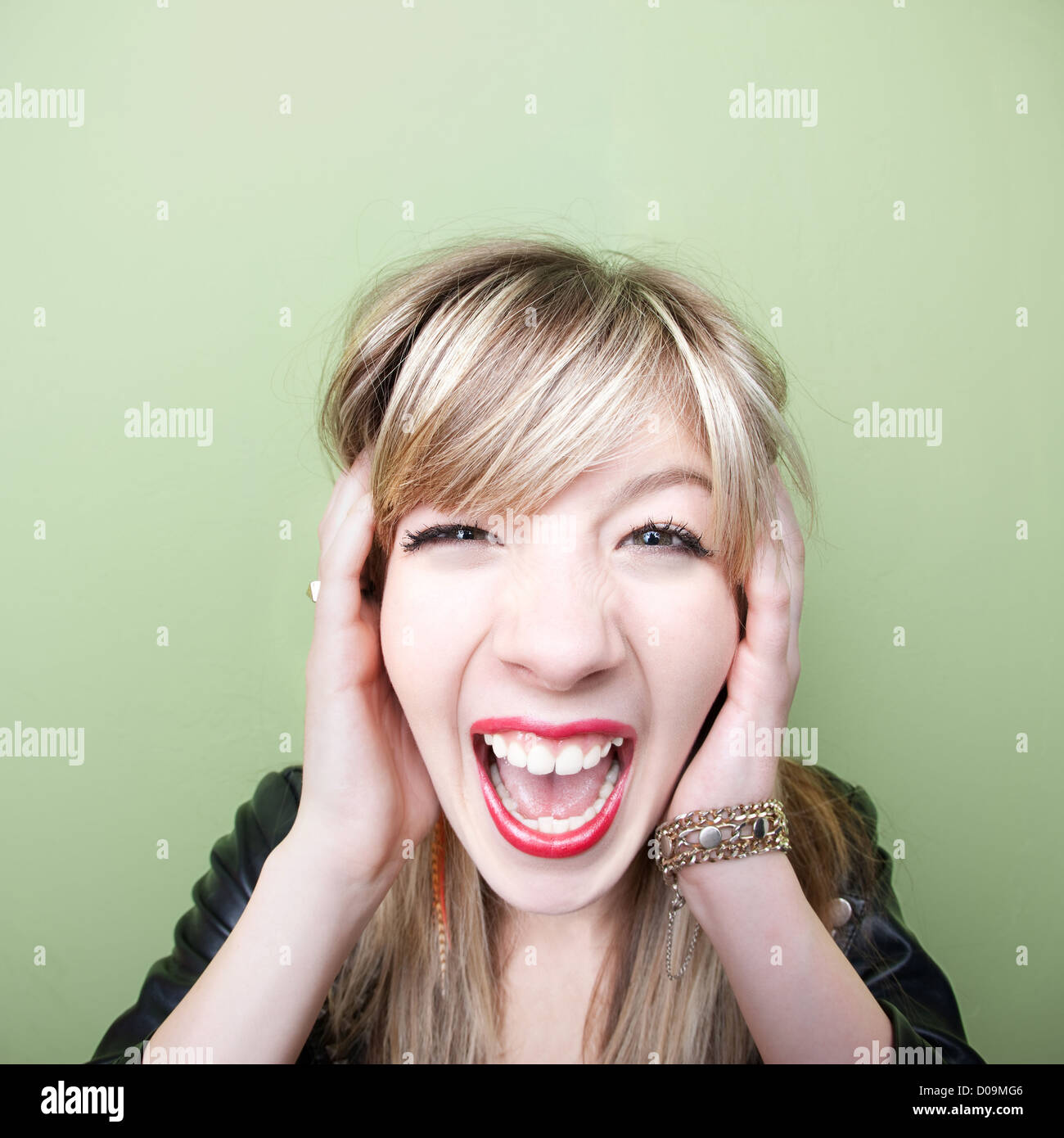 Young Caucasian woman screams with ears covered Stock Photo