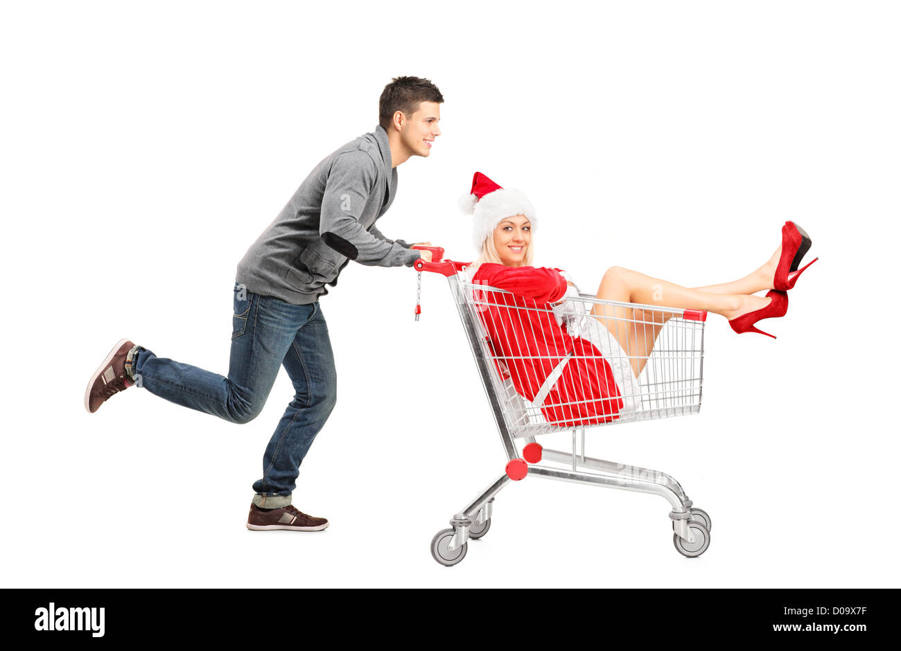 A guy pushing a woman wearing christmas costume in a shopping cart