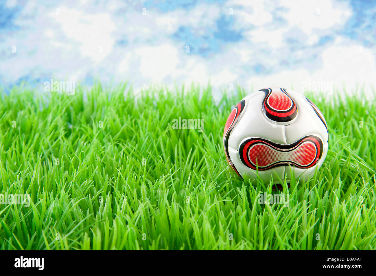 Soccer ball on grass against blue cloudy sky Stock Photo