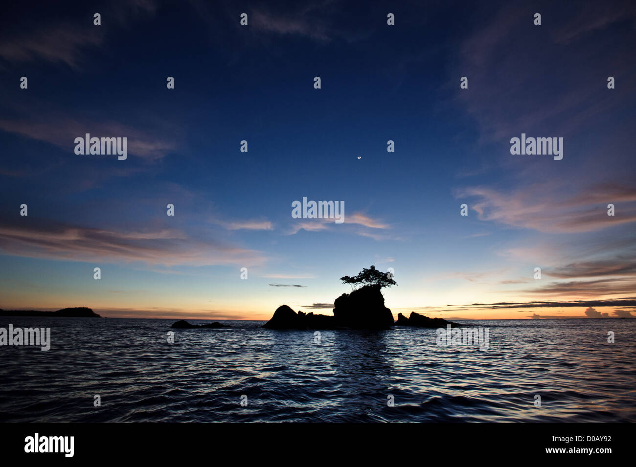 a rocky formation with a mangrove tree in the middle of the sea in the Mentawai, West Sumatra, Indonesia . During sunset Stock Photo