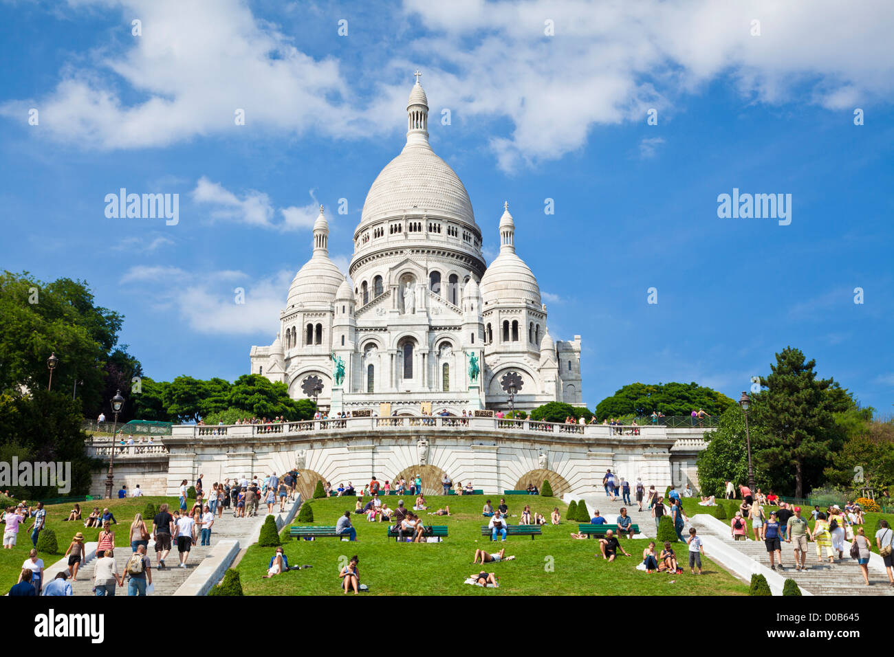 Crowds sat on the grass below Sacre Coeur in the Square Louise Michel Paris France EU Europe Stock Photo
