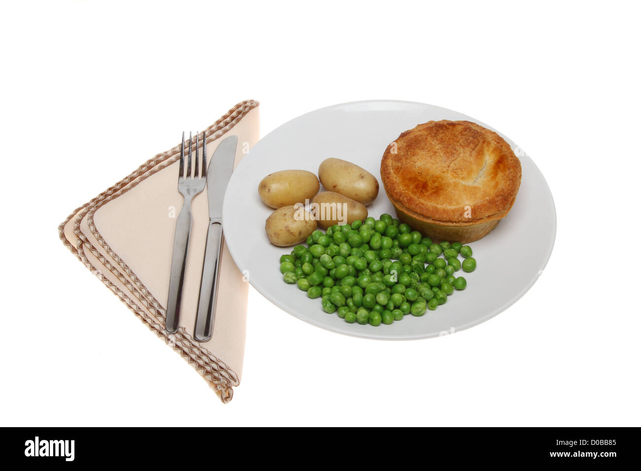 Meat pie and vegetables on a plate alongside a knife and fork on a napkin isolated against white Stock Photo