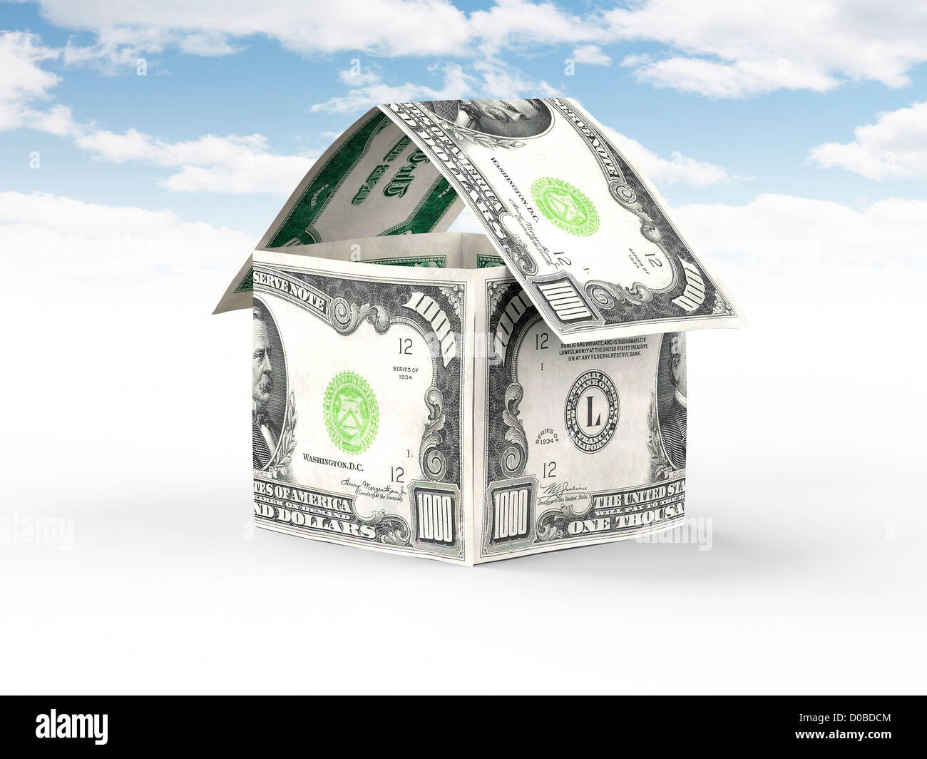 House made of money, thousand US dollar bills standing under blue sky isolated on white background Property, real estate concept Stock Photo