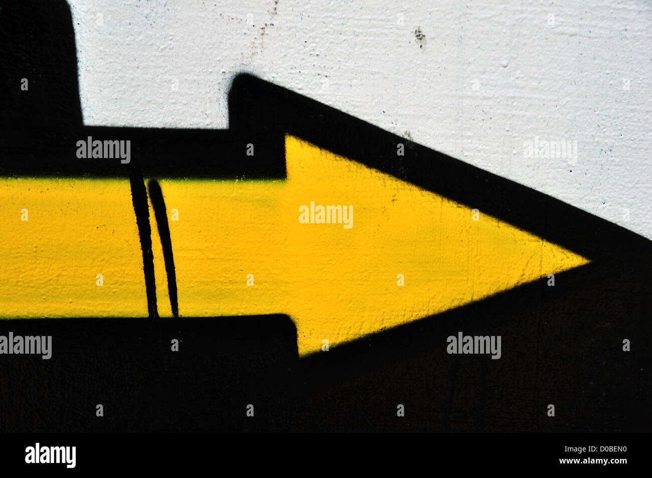 Yellow arrow graffiti sprayed on wall. Abstract background texture. Stock Photo