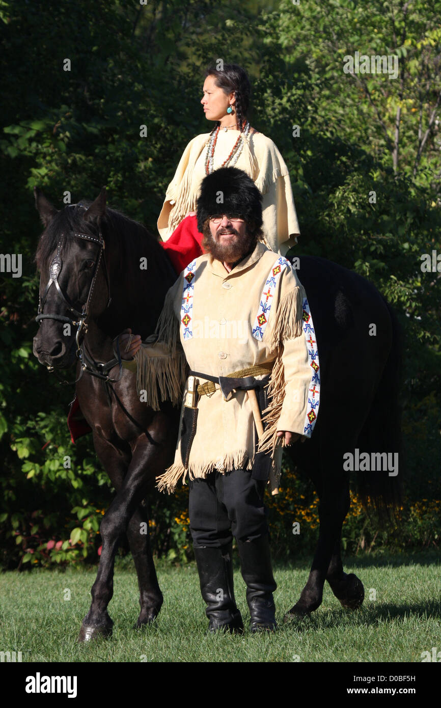 A Native American Indian woman riding a black horse with a pioneer ...