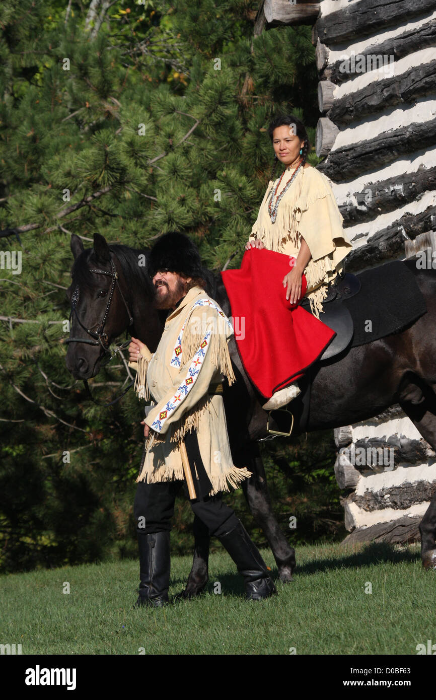 A Native American Indian woman riding a black horse with a pioneer ...