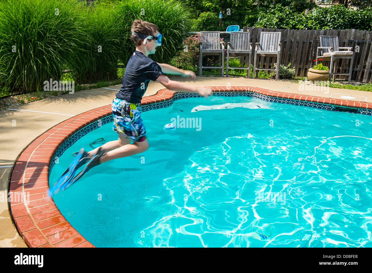 Boy jumping into a pool with flippers and goggles Stock Photo Alamy
