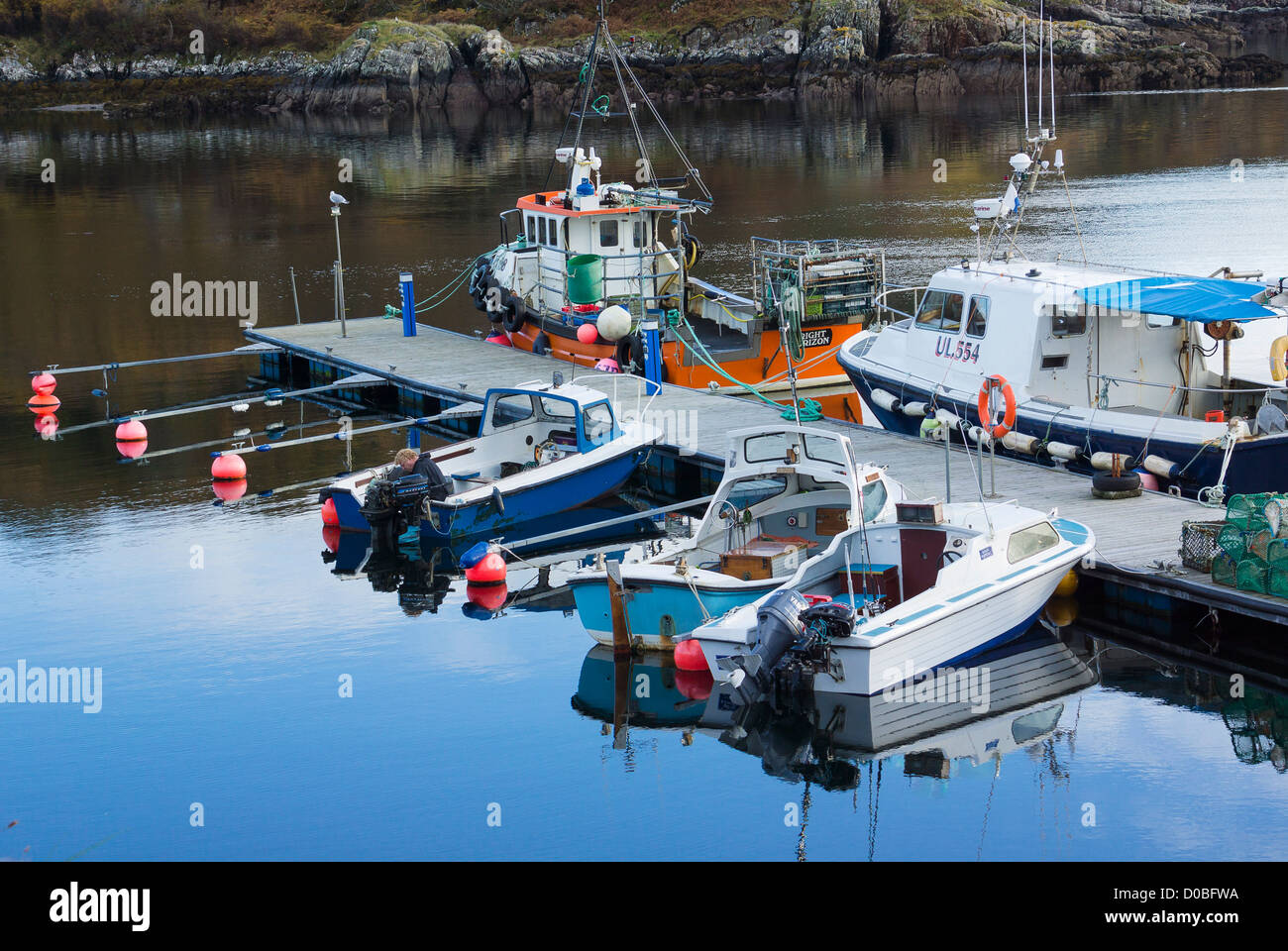 Fishing trawlers and recreational boats reflected in the still waters at Charlestown harbor at Gairloch. Stock Photo