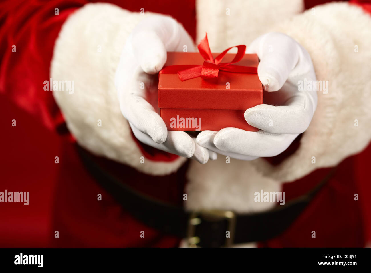 Photo of Santa Claus gloved hands holding red giftbox Stock Photo - Alamy