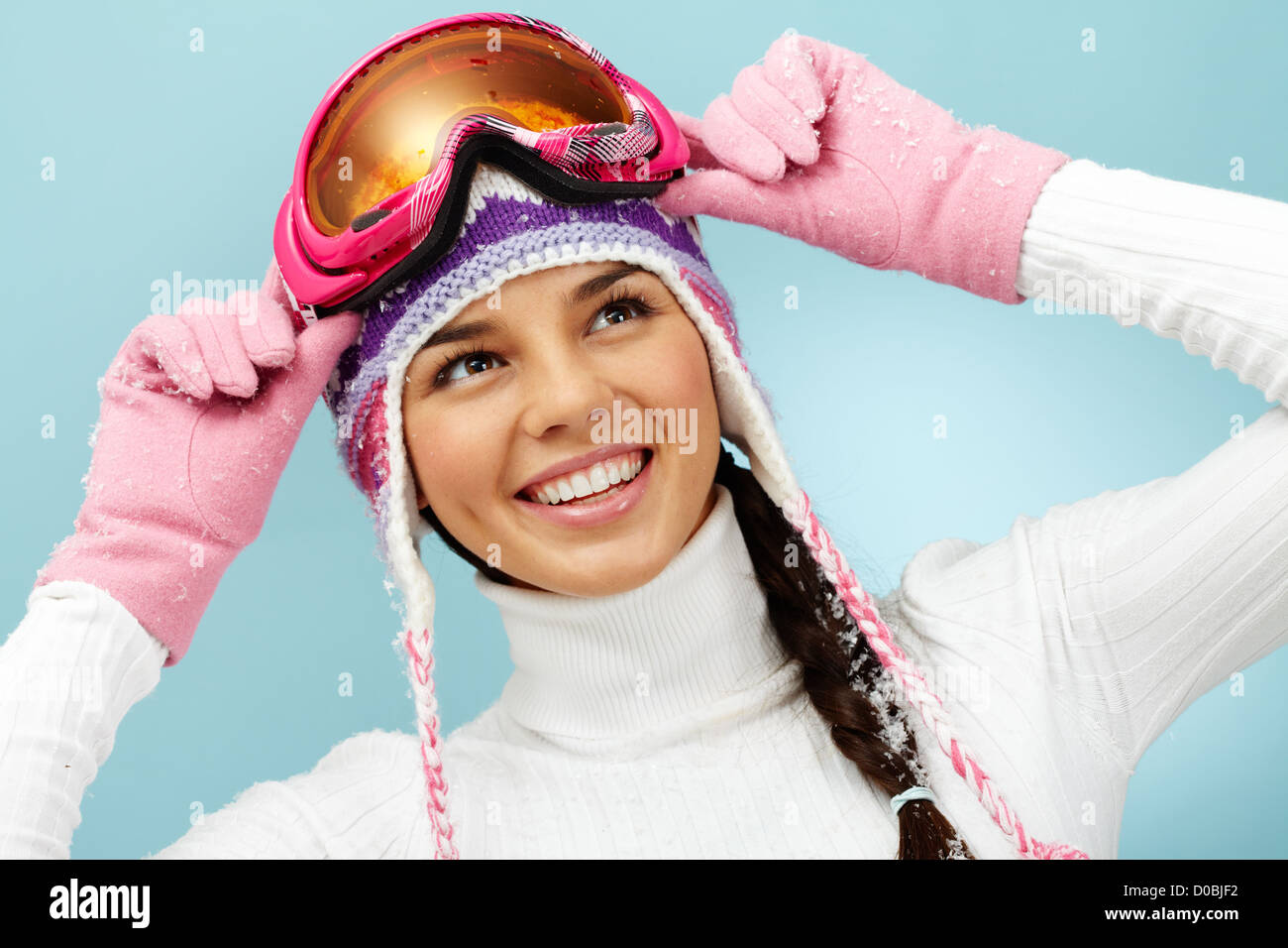 Pretty woman in goggles and knitted winter cap looking upwards with smile Stock Photo