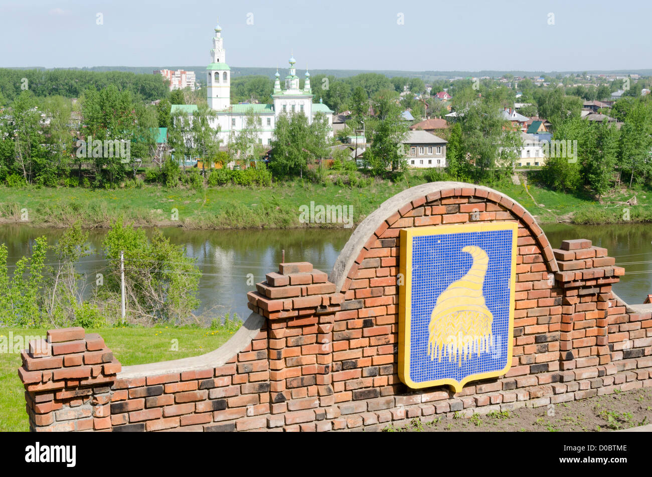 Wall with Horn of Plenty symbol, Kungur, Urals, Russia.  River and Russian orthodox church behind Stock Photo