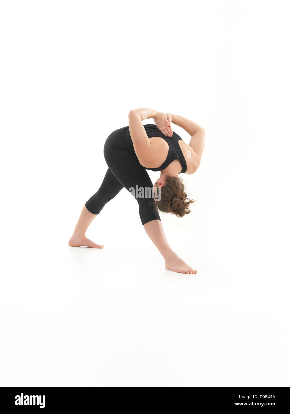 young blonde woman dmonstrationg yoga pose, bent fowrad, with face obscured, dressed in blak, on white background Stock Photo