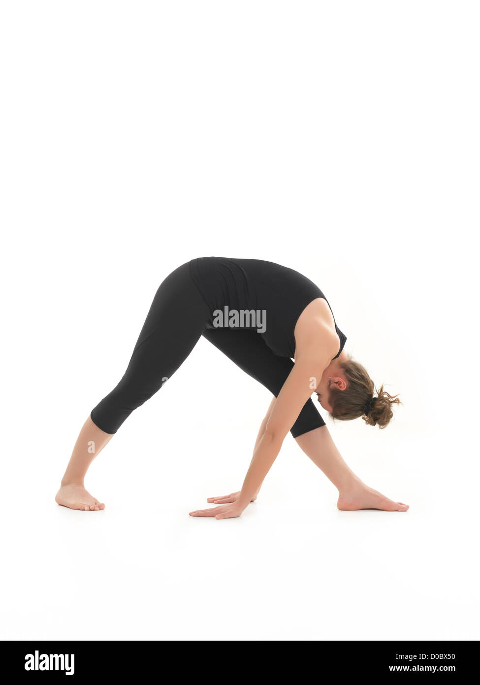 side view of young woman in yoga posture, face obscuredm dressed in blak, on white backgrond Stock Photo