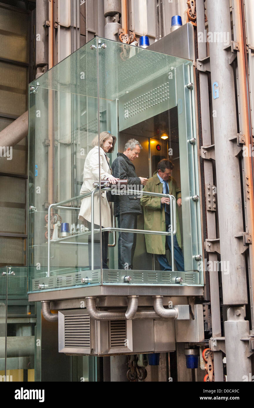London City detail of The Lloyds Building glass lift on outside wall with passengers blue lights Stock Photo