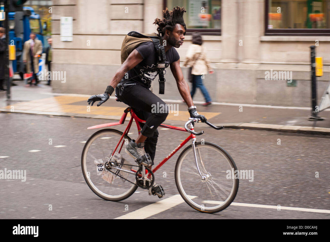 London , City , black man boy male messenger on bike bicycle cycle biker with Afro hair hairstyle Stock Photo