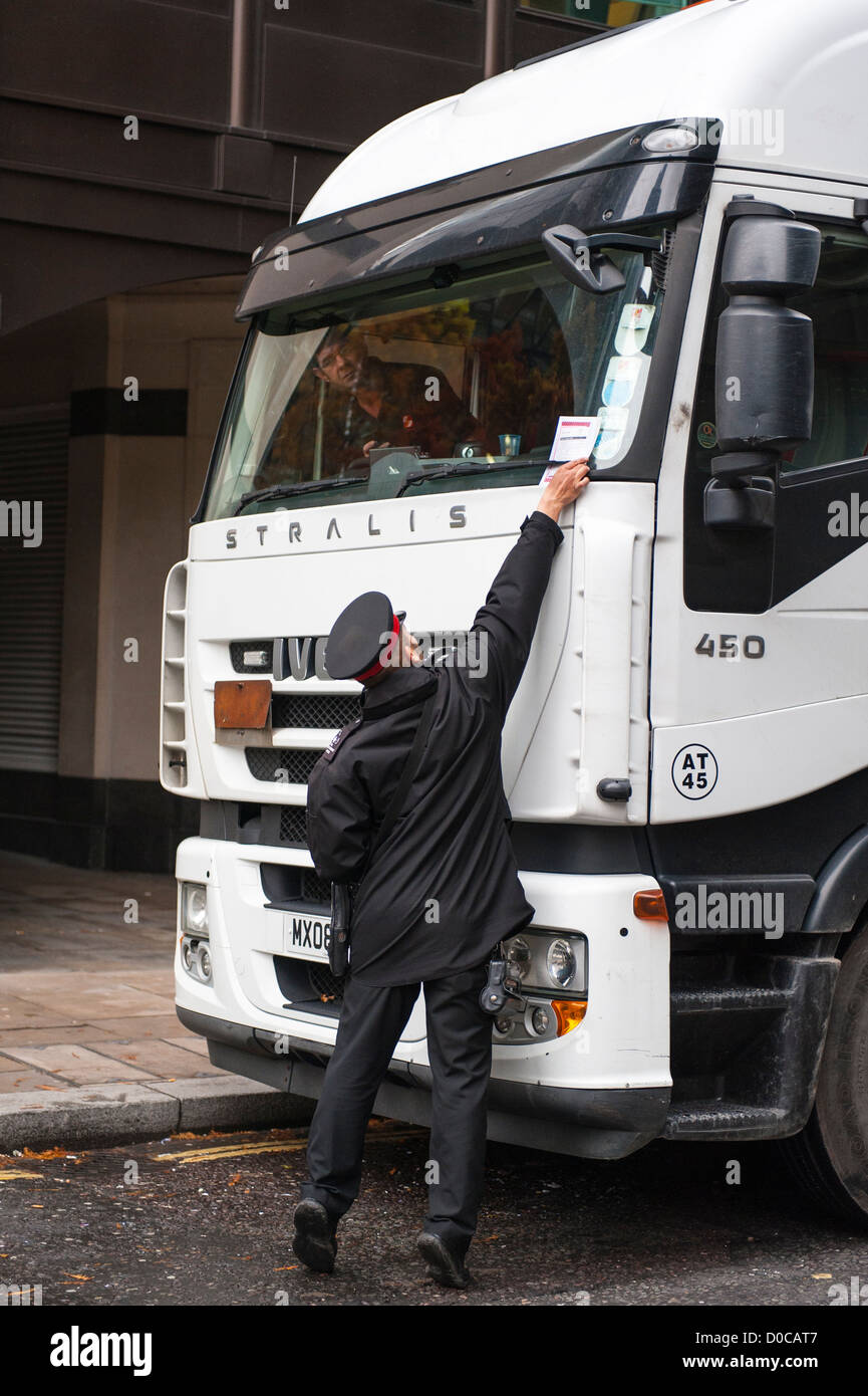 London City traffic warden uniform giving putting parking ticket PCN fine contravention on Iveco Stralis 450 white truck lorry driver in cab Stock Photo