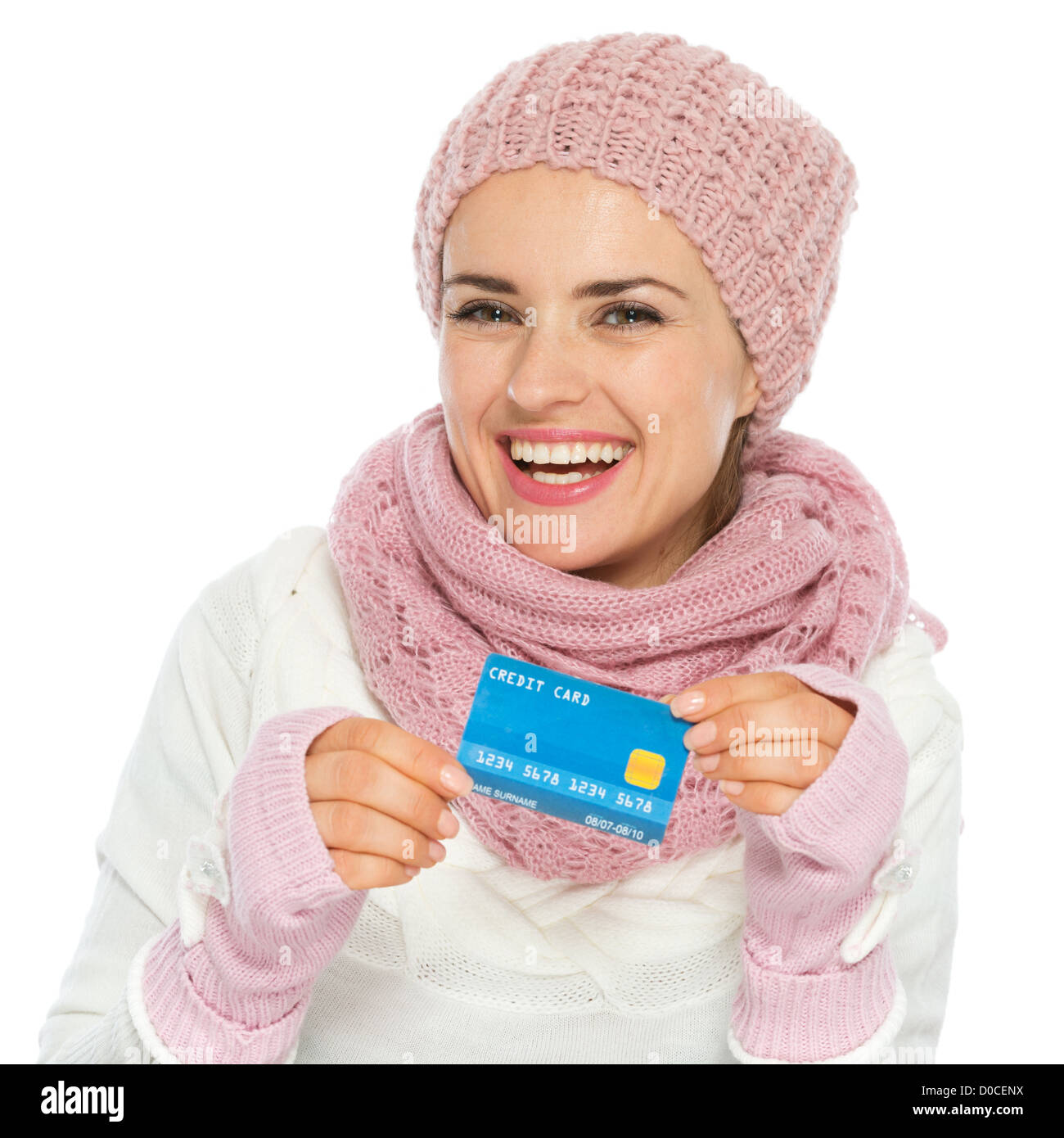 Smiling woman in knit scarf, hat and mittens holding credit card Stock Photo