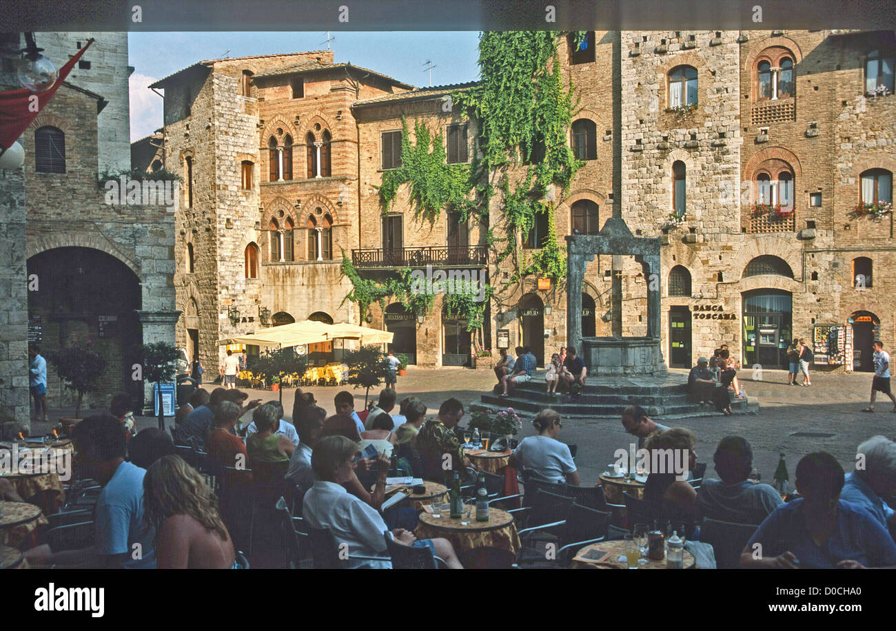 VISITORS EXPLORE HISTORIC GIMIGNANO SIENA  TUSCANY  NORTHERN ITALY SUNDOWNERS IN THE TOWN SQUARE Stock Photo