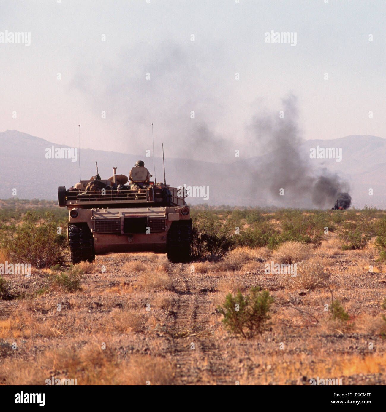 M1A1 Abrams Battle Tank Approaches a Smoking Hulk Just Hit by its Main Gun Stock Photo