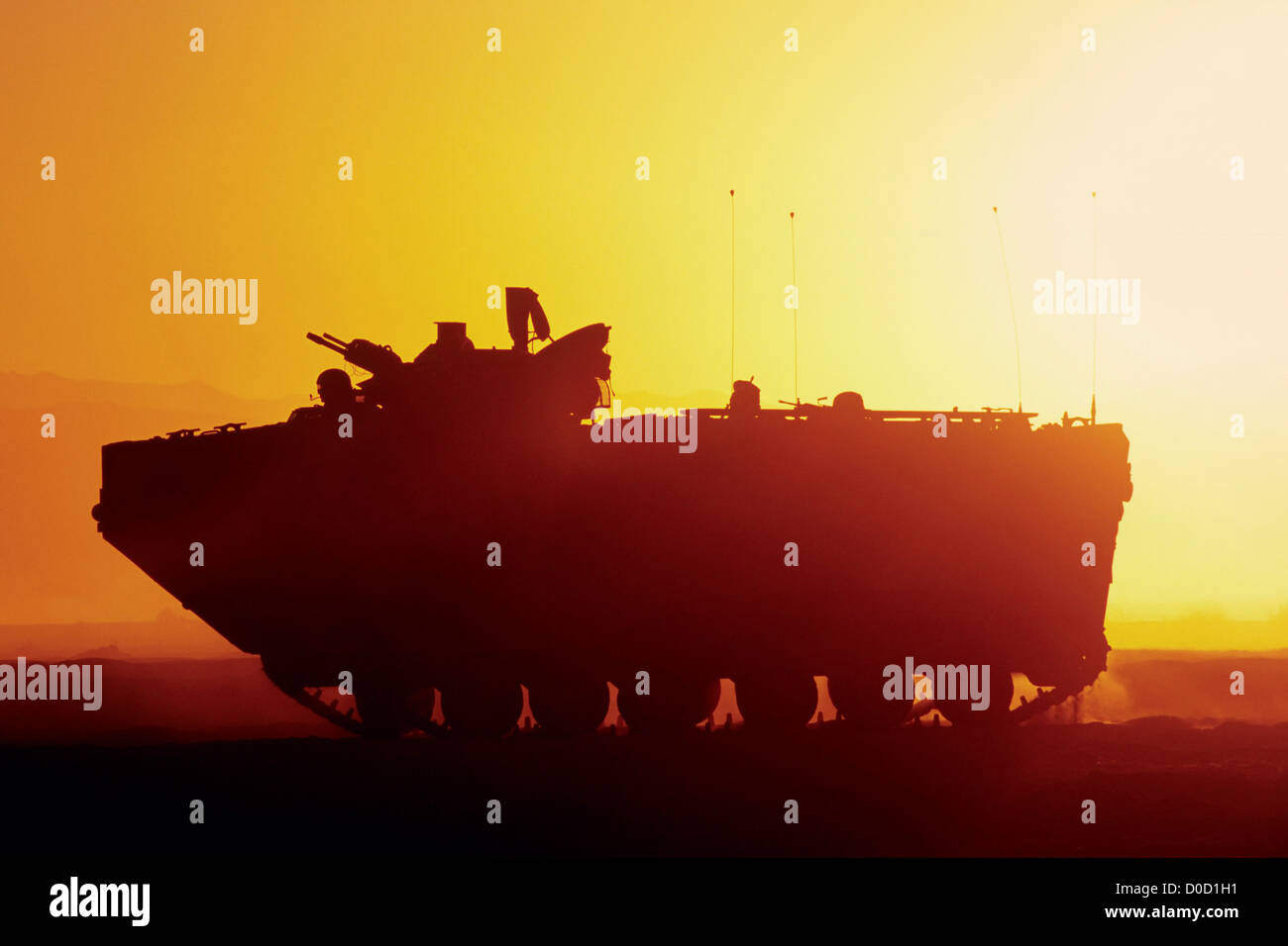The Setting Sun Silhouettes an Amphibious Assault Vehicle During a Training Exercise Stock Photo