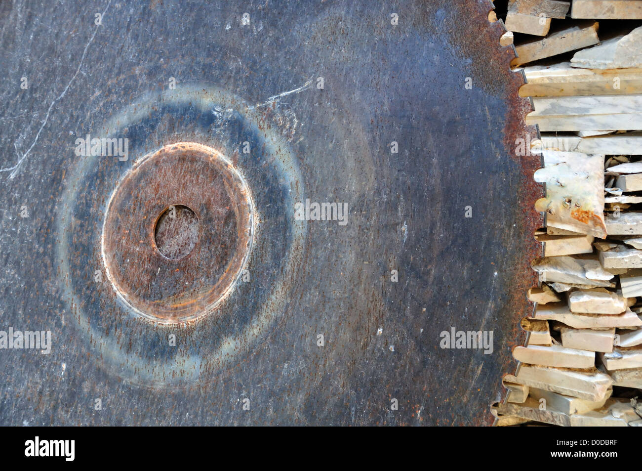 Vintage cutting wheel and pile of marble scrap. Rusty industrial equipment. Stock Photo