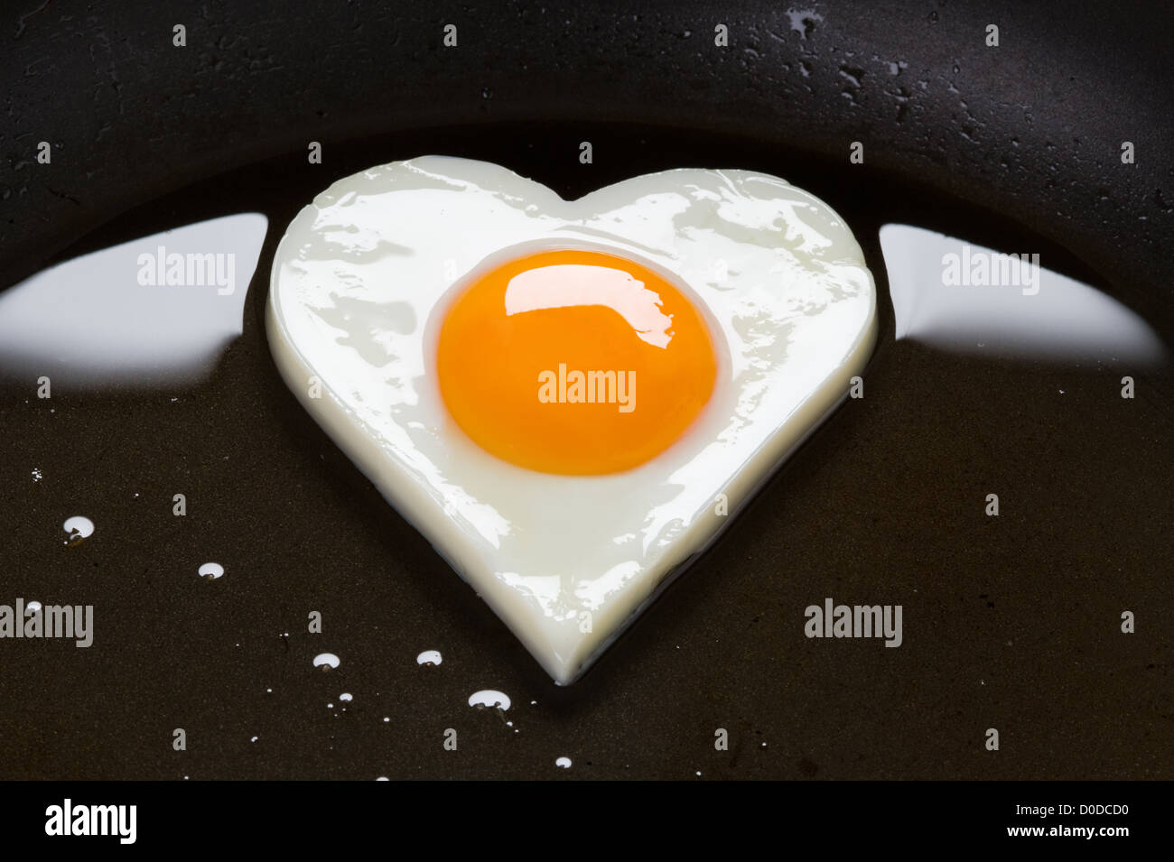 fried egg. heart shaped hens egg cooking in oil in a frying pan to make fried egg in the shape of a heart Stock Photo