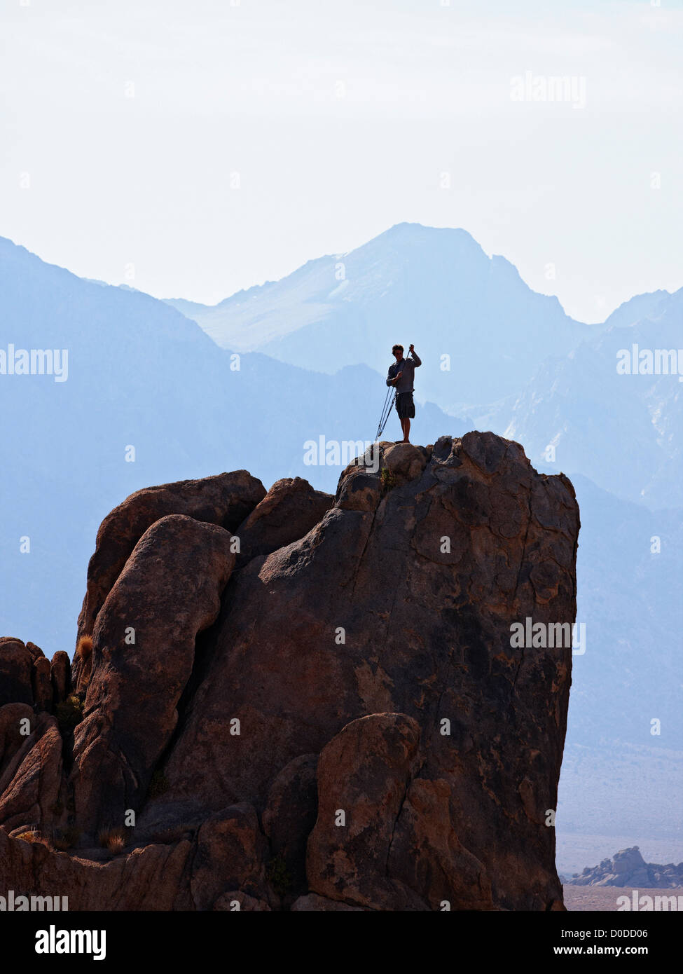 A climber sets up rope in preparation rappel down face cliff in California's Alabama Hills below