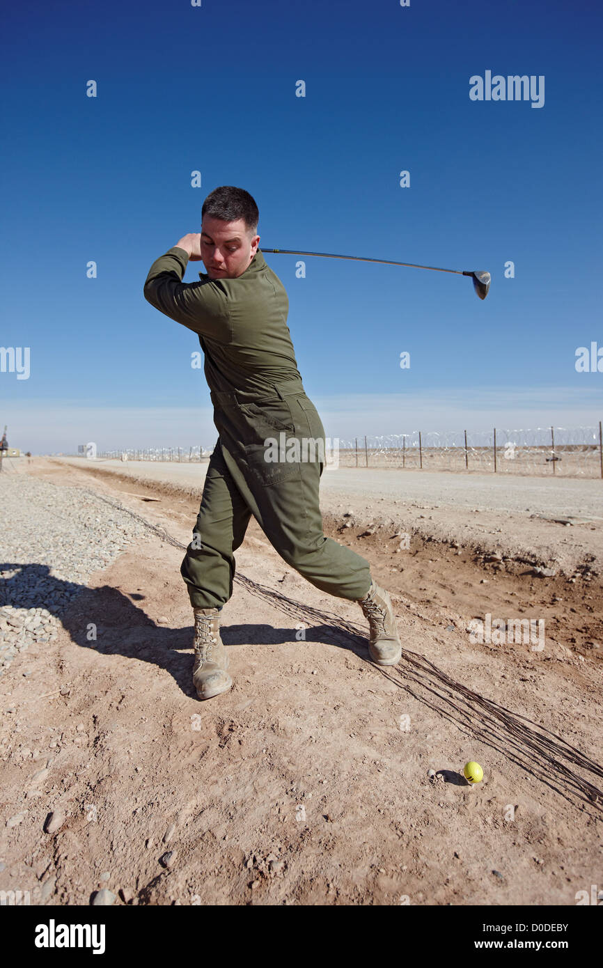 A U.S. Marine hits a golf ball into the desert at Camp Bastion, Helmand Province, Afghanistan. Stock Photo