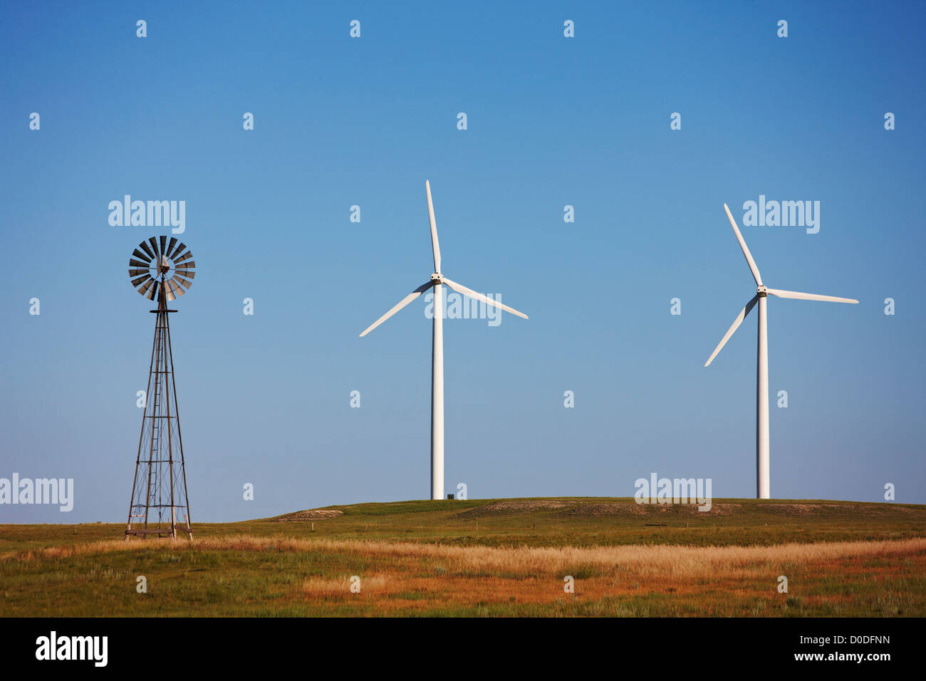 One water pumping windmill next to two electricity generating wind turbines. Stock Photo