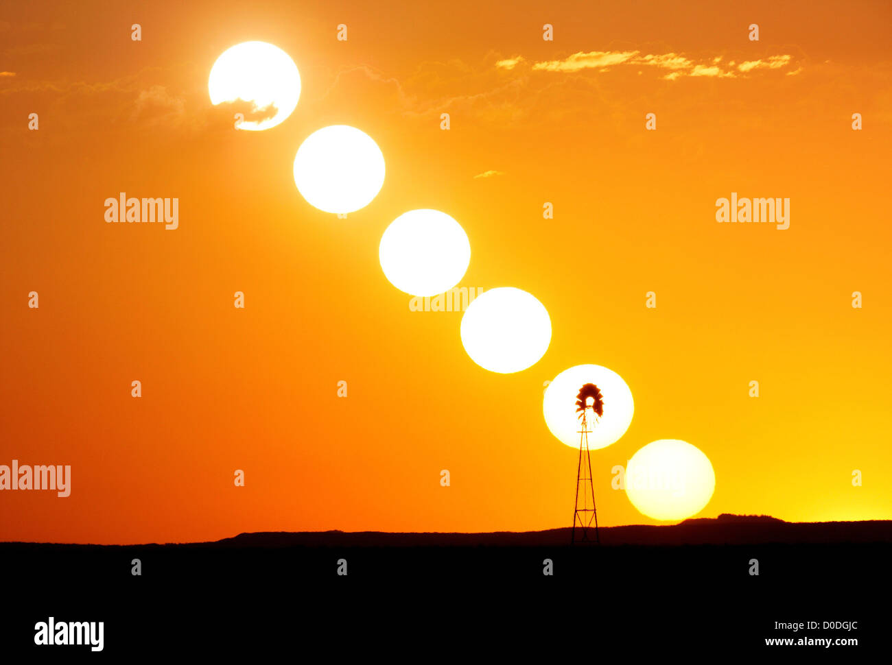Sequence of the sun setting, silhouetting a lone windmill on plains, Colorado, USA Stock Photo