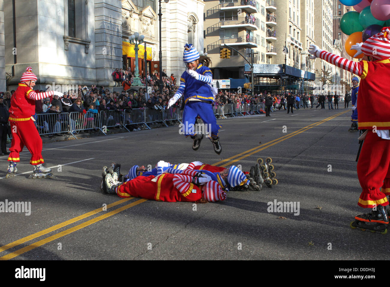 Spectators watch a clown on roller blades jump over other clowns on Central Park West during Macy's Thanksgiving Day Parade in New York City, on Thursday, Nov. 22, 2012. Stock Photo