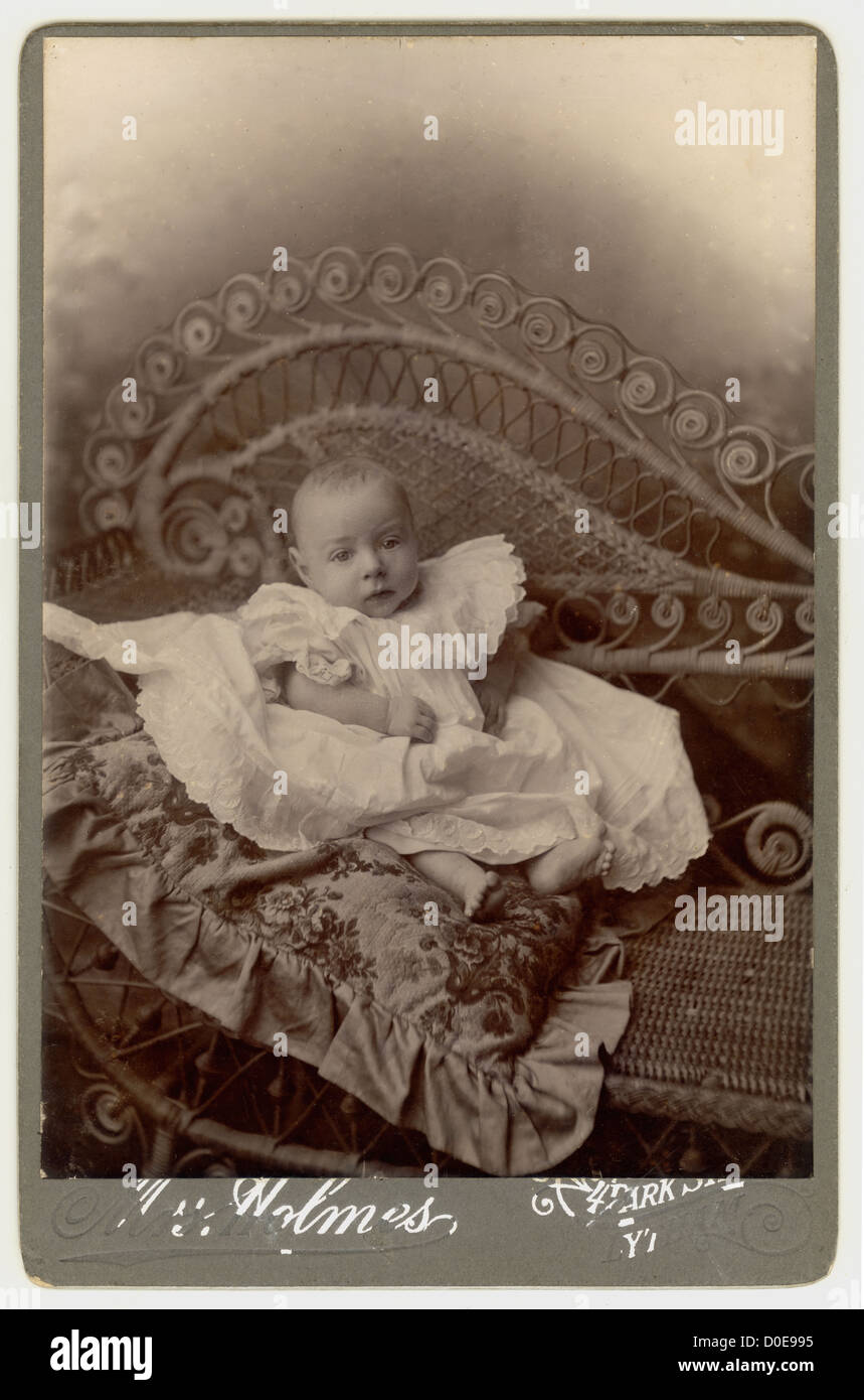 Victorian studio portrait of cute baby photographed on a cane or bamboo sofa, couch,  Lytham, Lancashire, England, U.K., circa 1890 Stock Photo