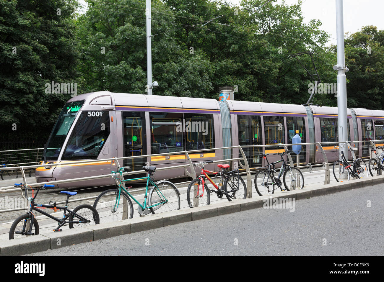 Luas Light Rail System tram in city centre station with bikes chained up to railings at Stephen's Green Dublin Southern Ireland Stock Photo
