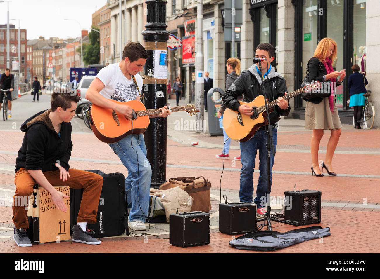 Typical street scene with three Irish musicians playing guitars busking in city centre on Grafton Street Dublin Ireland Eire Stock Photo