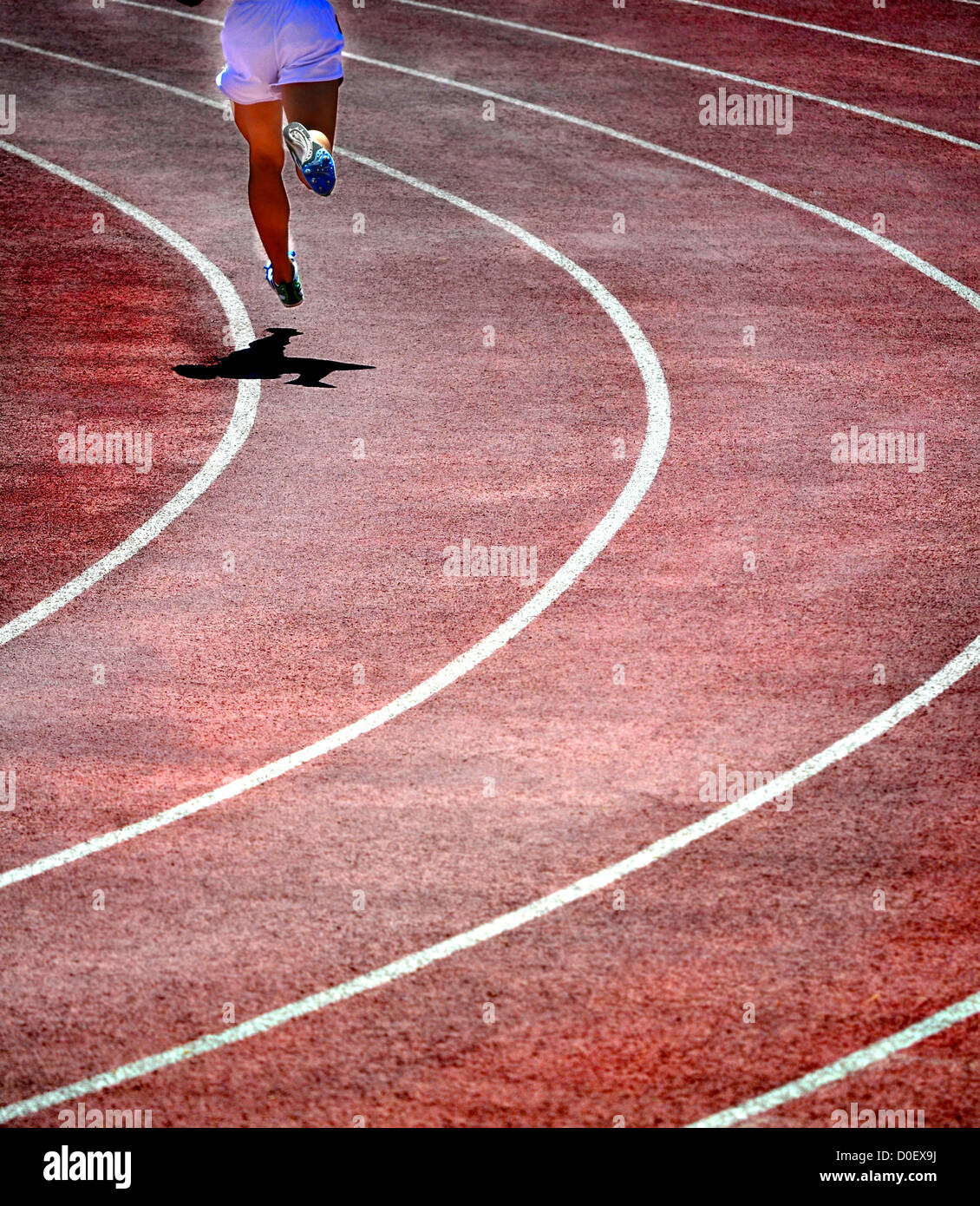 Runner on lanes of a red race track with a curve at the end Stock Photo