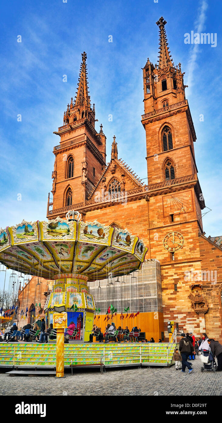A carousel by the Basel Minster (Basler Münster), one of the main landmarks of the city, during the 2012 Basel Fall Fair. Stock Photo