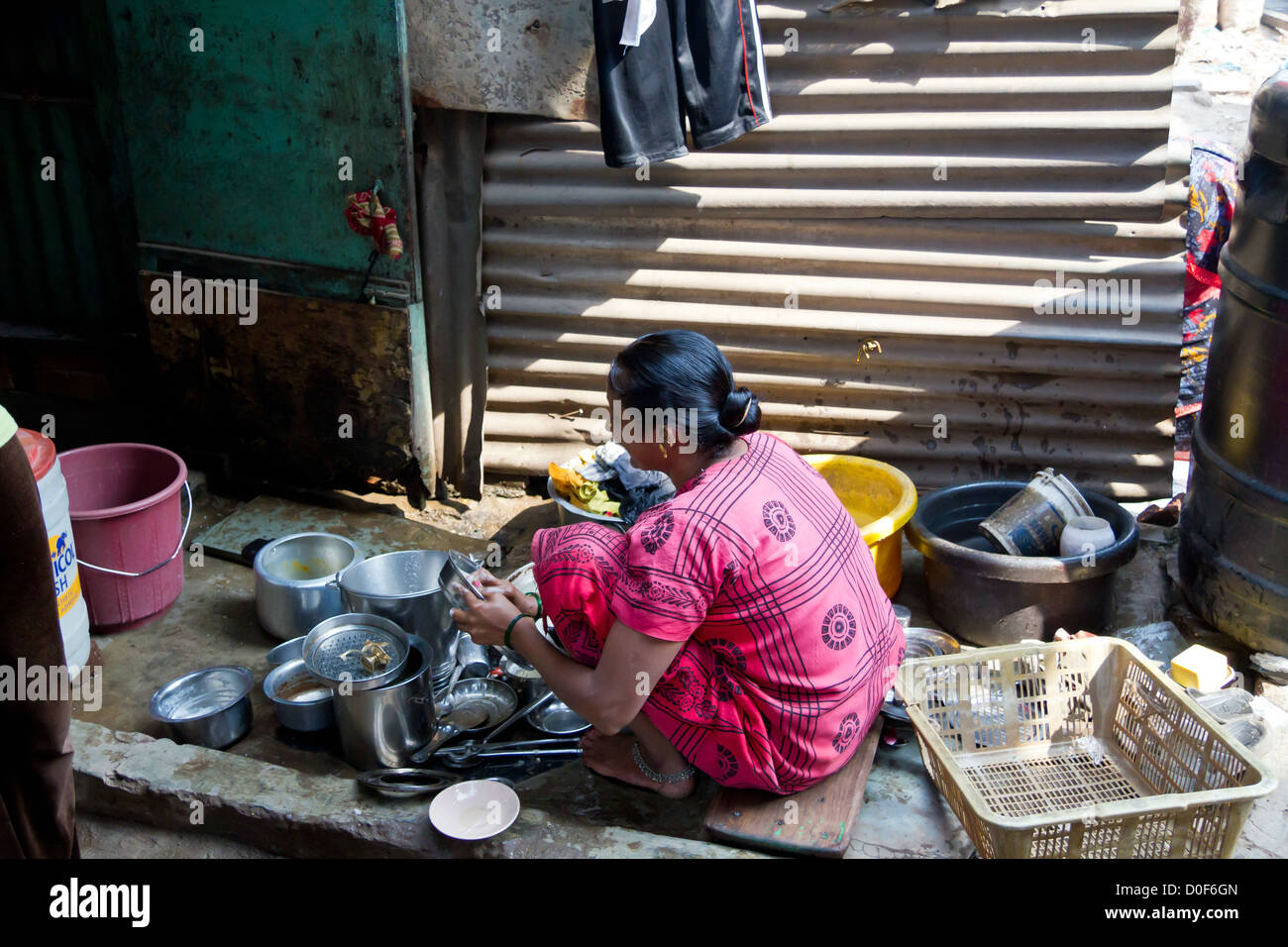 Woman washing the Dishes on the Street in the Dharavi Slum in Mumbai, India Stock Photo