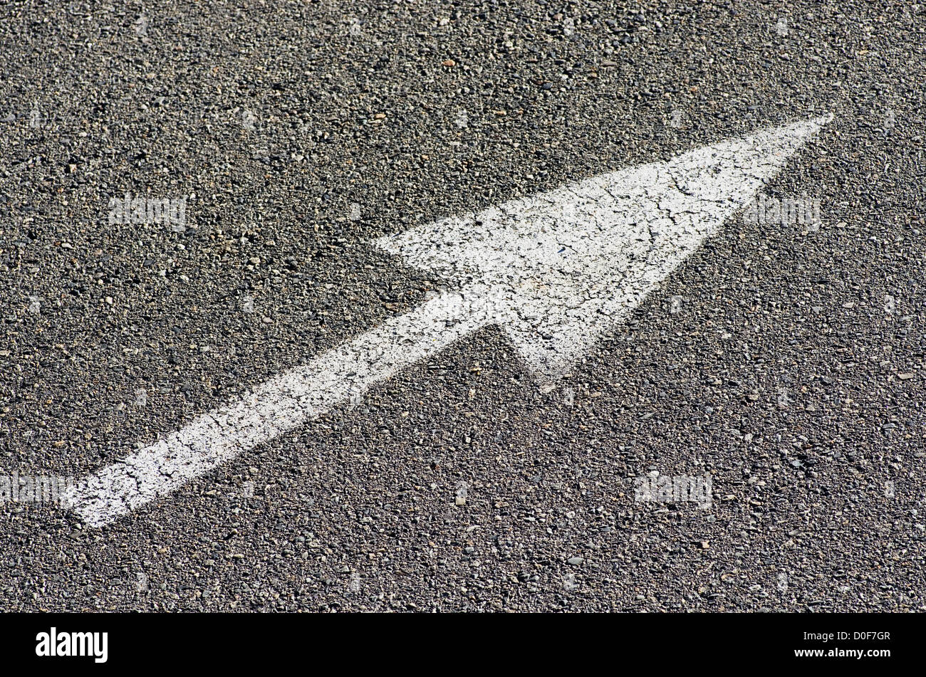 white arrow on gray asphalt pavement pointing up to the right Stock Photo