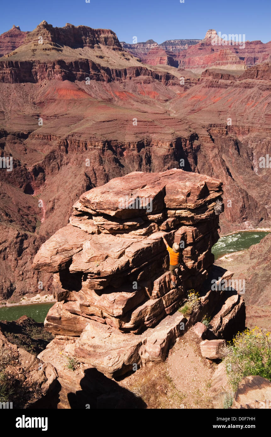 a man climbing a rock pinnacle at Plateau Point in the Grand Canyon Stock Photo