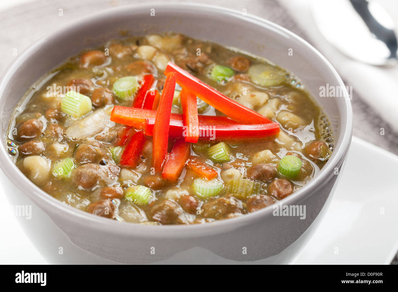 Bowl of fresh soup with kapucijners, green onions, and red bell pepper garnish Stock Photo