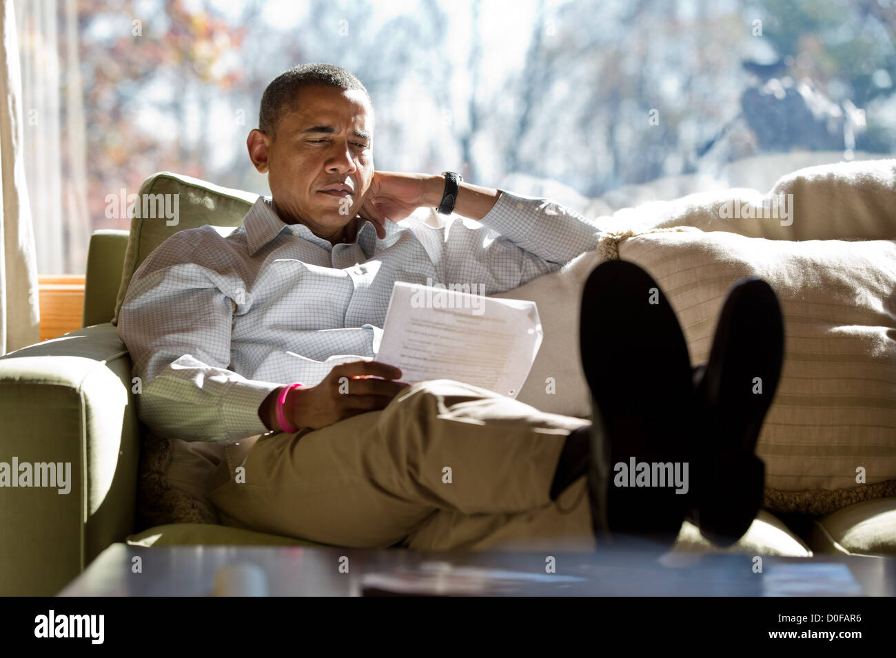 US President Barack Obama reads briefing material while meeting with advisors October 21, 2012 inside his cabin at Camp David. Stock Photo