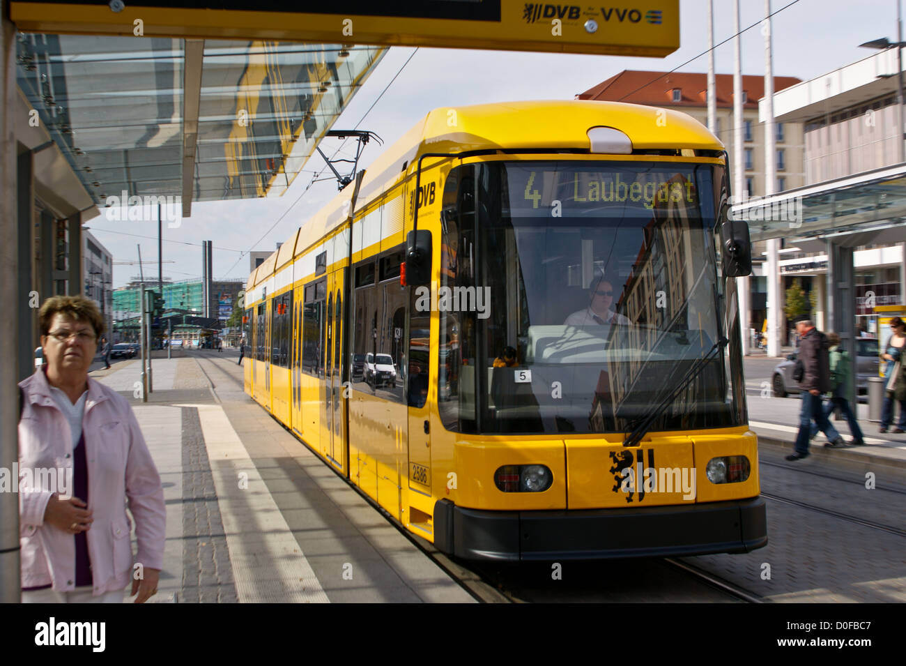 A tram, strassenbahn, approaching a stop, Alter Markt, Dresden, Sachsen, Saxony, Germany with a woman waiting Stock Photo