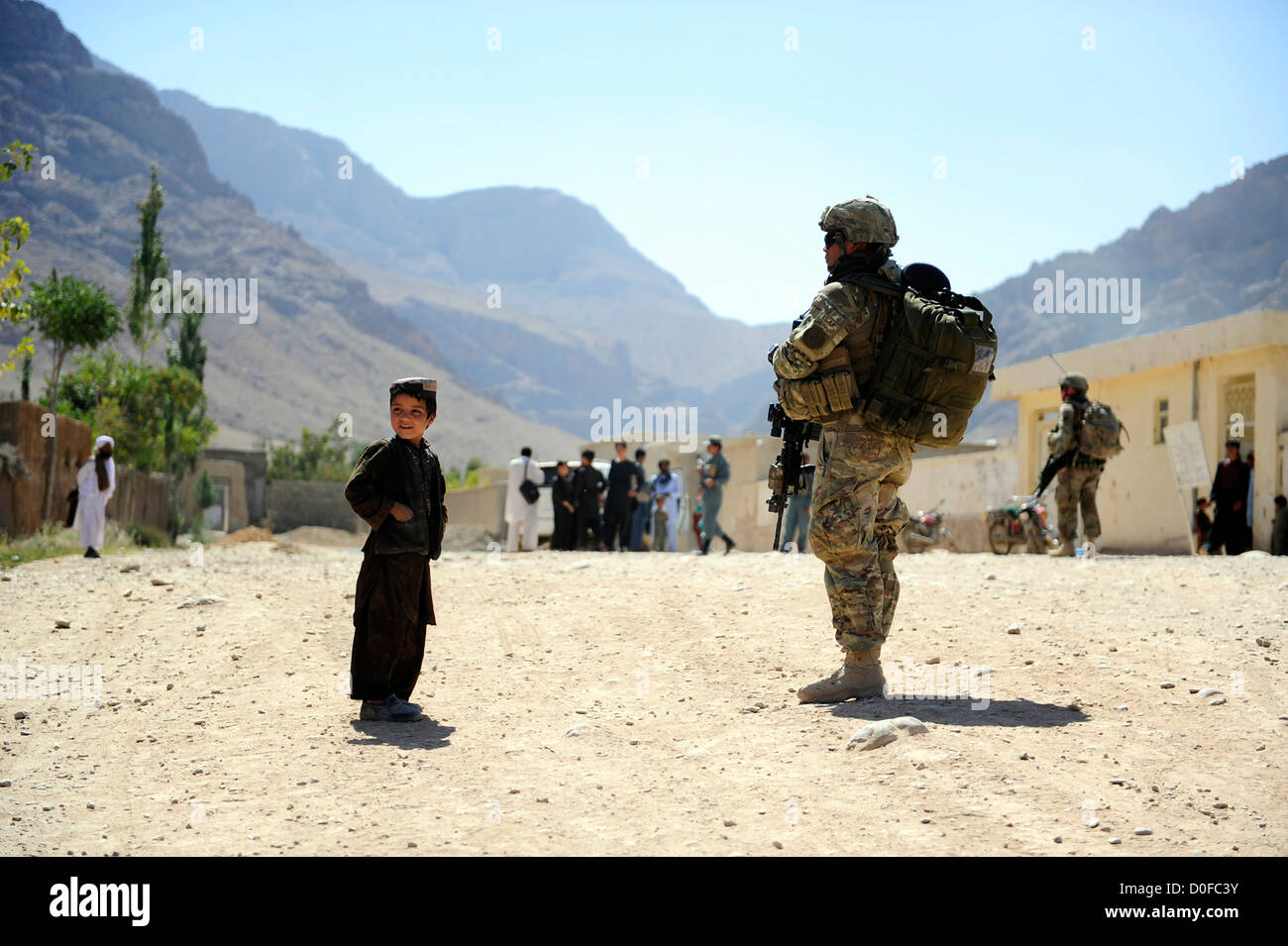 A local Afghan boy looks on as a US Navy corpsman secures a village September 26, 2012 during a mission to Pur Chaman district, Farah province, Afghanistan, Sept. 26. The mission marks the first time coalition forces have been to the Pur Chaman district in over a year. Stock Photo